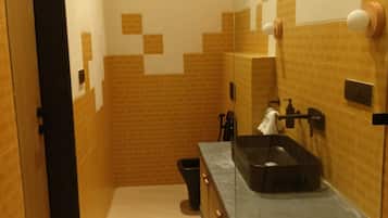 A bathroom with a tiled wall, a sink, and a mirror.