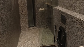 Un baño pequeño y privado con ducha, inodoro y lavamanos.