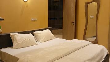 Una habitación de hotel con una cama, una mesita de noche, un espejo y un equipo de aire acondicionado en la pared.