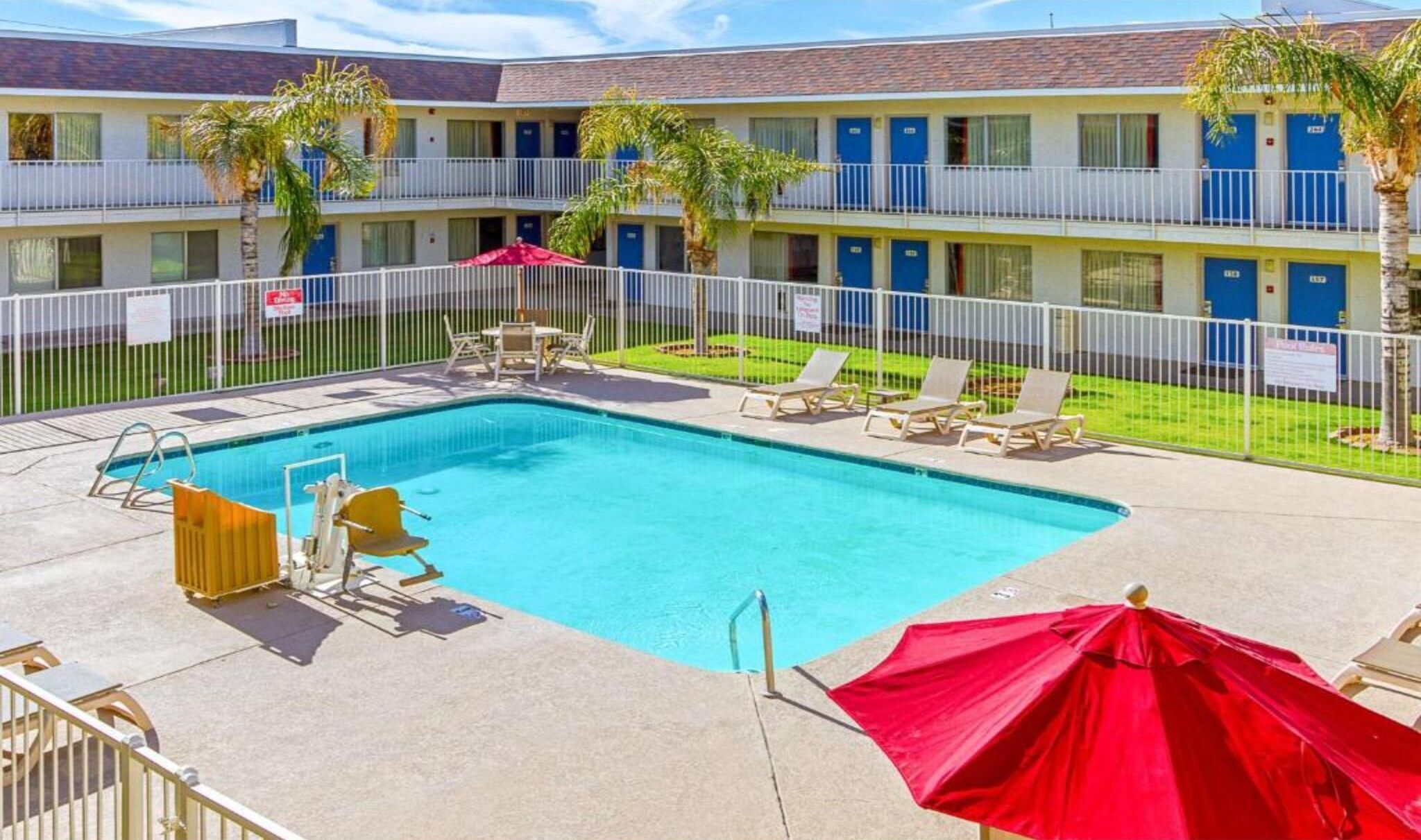 A pool area with lounge chairs and umbrellas, surrounded by a fenced pool deck.