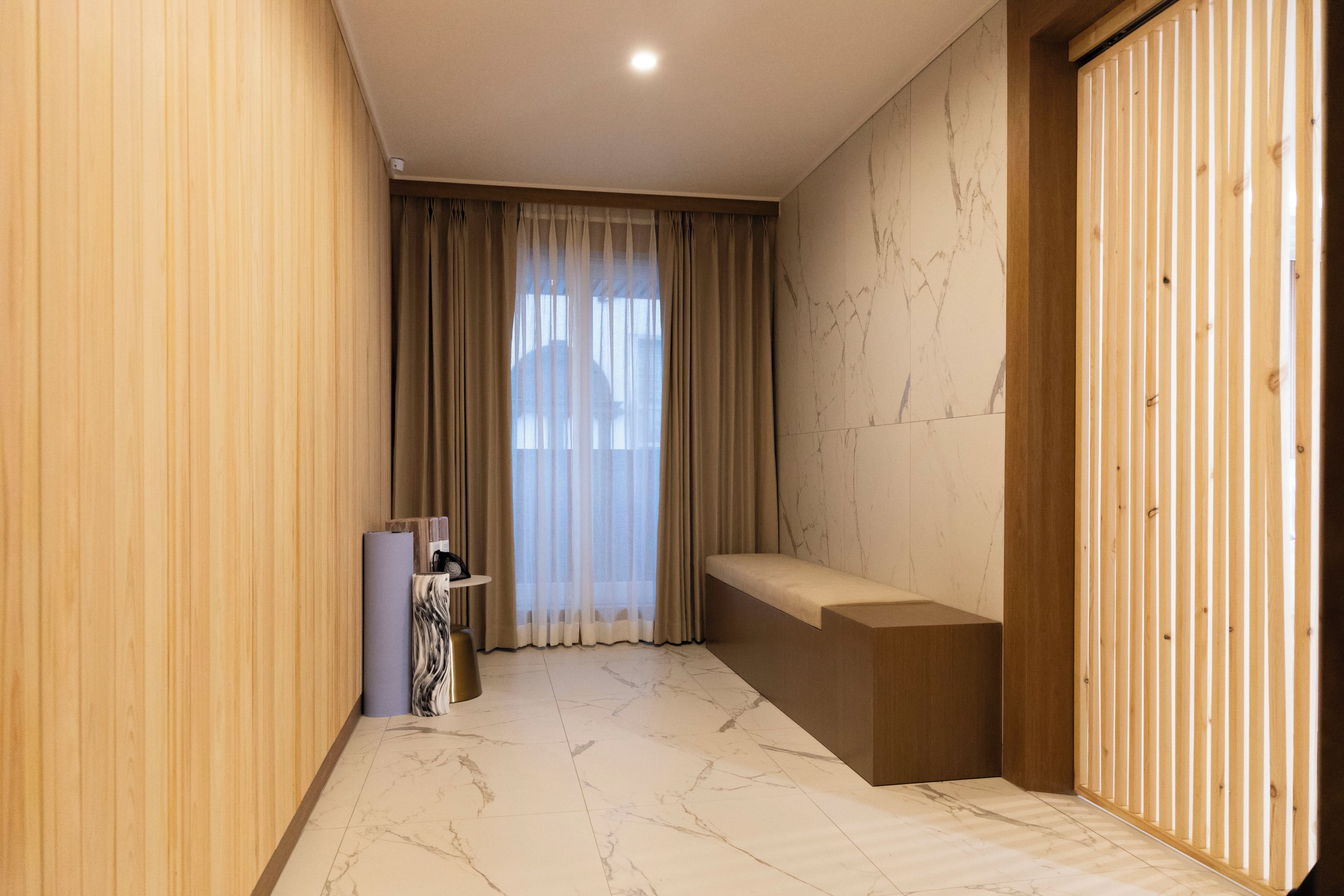 Un baño moderno con piso de mármol, un banco y un separador de madera.