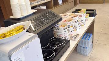 Ein reichhaltiges Buffet mit einer Kaffeemaschine, Warmhalteplatten und verschiedenen Behältern für Speisen.