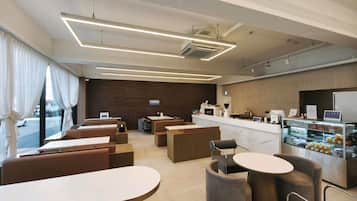 Un café moderno con mesas, una barra y una vitrina con alimentos.