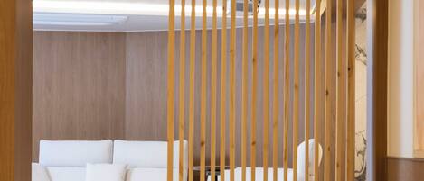 A modern living room with a white sofa, a beige armchair, and a wooden partition.