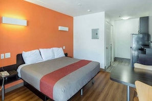 Une chambre d’hôtel avec un lit, un bureau et une chaise.