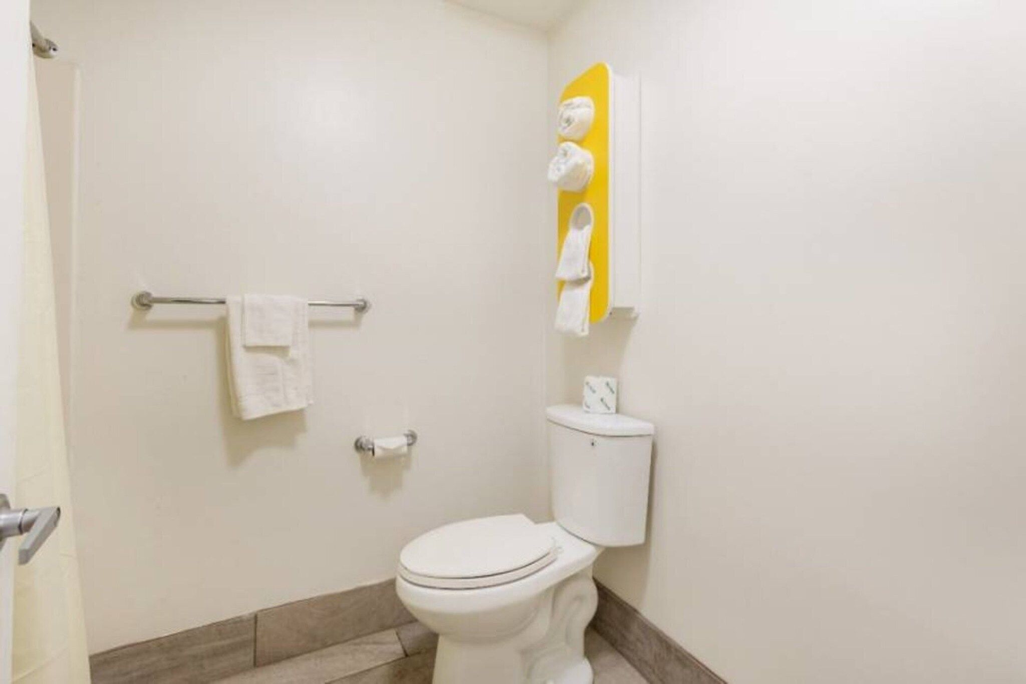 A bathroom with a toilet, a towel rack, and a toilet paper holder.