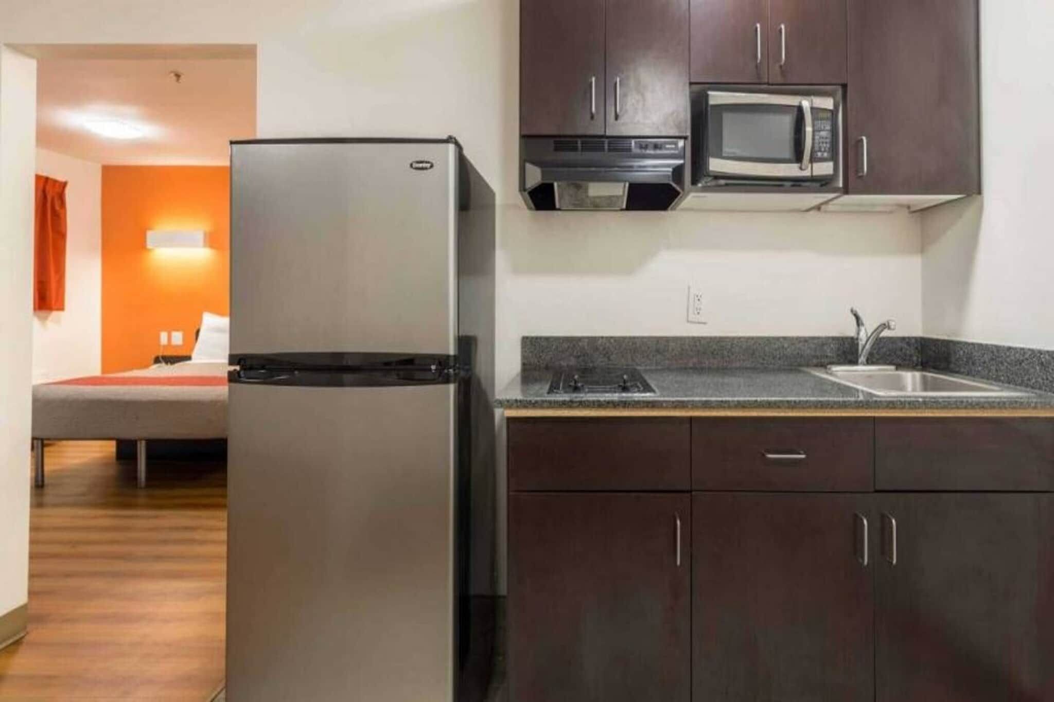 A compact kitchen with a refrigerator, microwave, and a sink.