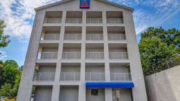A multi-story building with a flat roof, a central entrance, and a sign above the entrance.