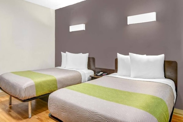 Two twin beds with white pillows and green blankets in a room with a wooden floor and grey walls. - 2 Full bed | Smoking (CHAMBLEE)