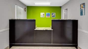 A reception area with a green wall, two framed pictures, a clock, and a door.