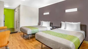 Ett hotellrum med två sängar, ett skrivbord och en stol.