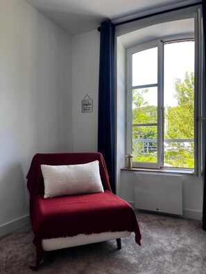 Ein Eckzimmer mit Bett, Fenster und Heizkörper.