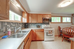 A kitchen with wooden cabinets, a stainless steel sink, a microwave, and a stove. - Kenosha Mid-Term Rental w/ Fenced Yard (Kenosha)