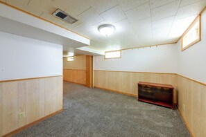 A room with a carpeted floor, wooden paneling on the walls, a ceiling vent, and a small window. - Kenosha Mid-Term Rental w/ Fenced Yard (Kenosha)