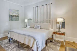 A neatly arranged bedroom with a bed, a bedside table with a lamp, a mirror, and a painting on the wall. - Pet Friendly Near UAB in Forest Park/East Avondale (Birmingham)
