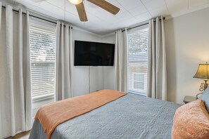 Ett sovrum med en säng, gardiner, en tv och en lampa.