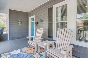 A porch with two wooden Adirondack chairs, a blue door, and a window with blinds. - Pet Friendly Near UAB in Forest Park/East Avondale (Birmingham)