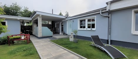 A modern house with a covered patio, a lawn, and a pool area.