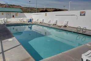 A swimming pool with lounge chairs and a lifeguard stand.