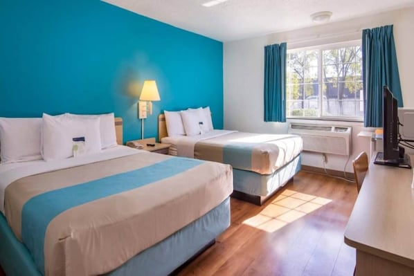A hotel room with two beds, a desk, a chair, a window with curtains, and a lamp. - 2 queen beds|mobility accessible|Nsmk (The Dalles)