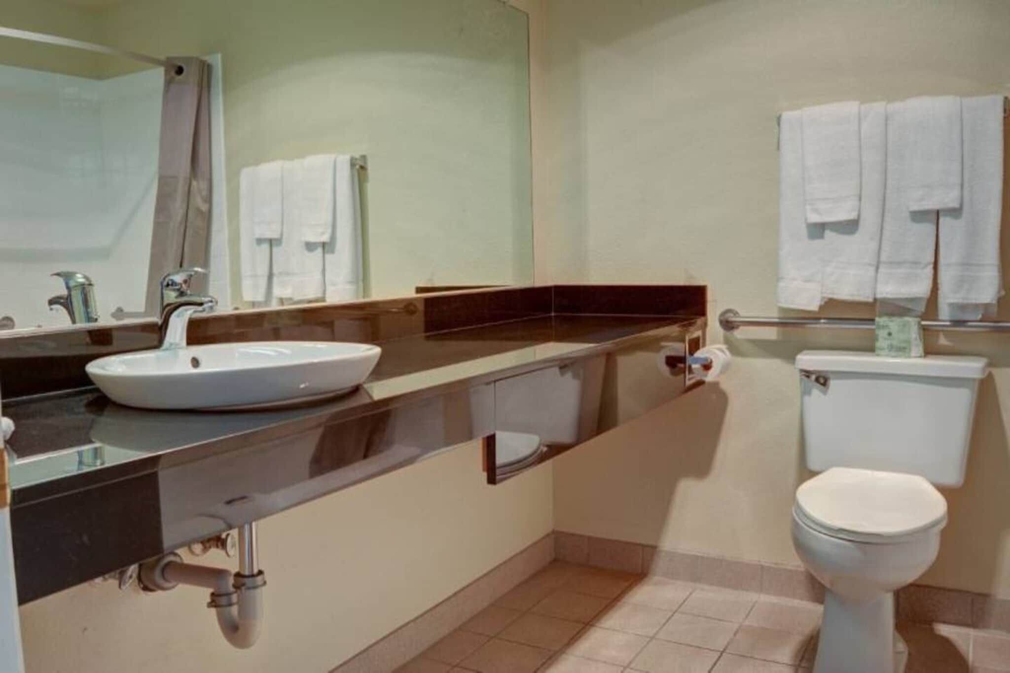 Ein Badezimmer mit Waschbecken, Spiegel, Toilette und Handtuchhalter.