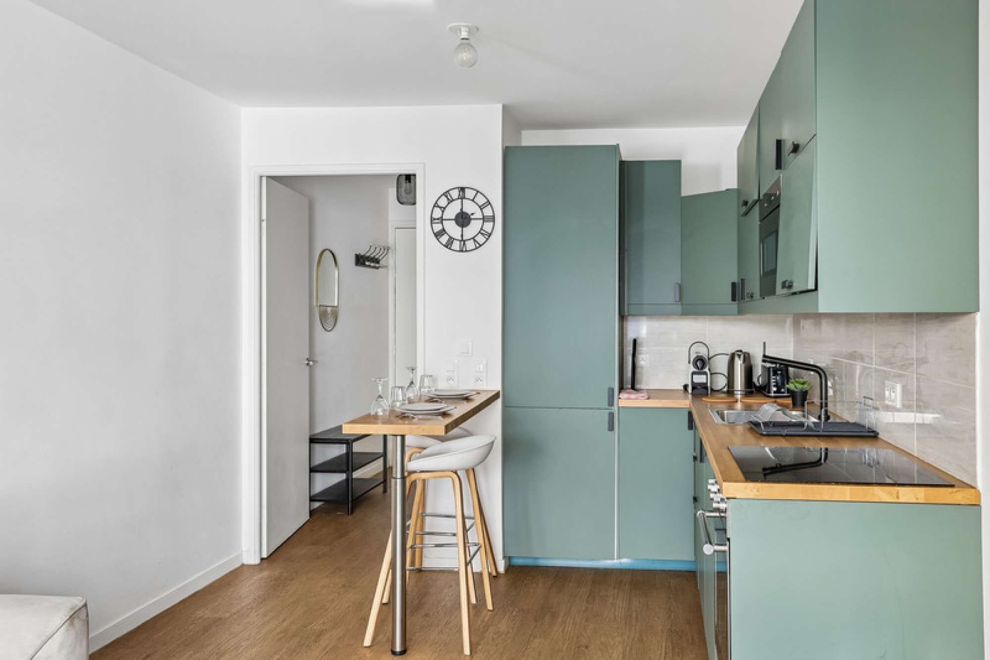 Een moderne keuken met blauwgroene kastjes, een houten aanrechtblad en een ingebouwde oven.