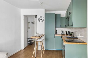 Una cocina moderna con gabinetes color turquesa, encimera de madera y horno empotrado.