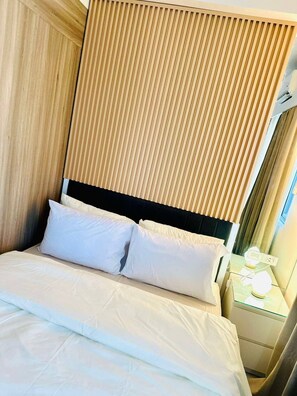 A hotel room with a bed, a nightstand, and a window with curtains. - Royal Fame Residence (Mandaluyong City)