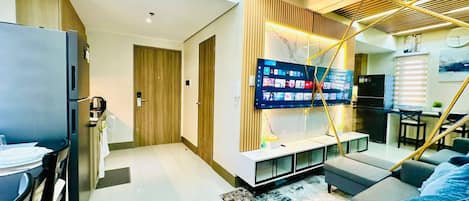 Una sala de estar moderna con un televisor de pantalla plana, un sofá y un comedor con mesa y sillas.