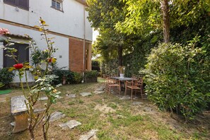 A garden with a table and chairs, a rose bush, and a brick wall. - Villa "Villino Arsella" with mountain view, balcony, and air conditioning (Pietrasanta)