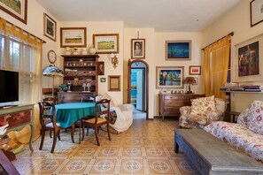 Un soggiorno con zona pranzo, televisione, libreria e una porta che dà su un'altra stanza.