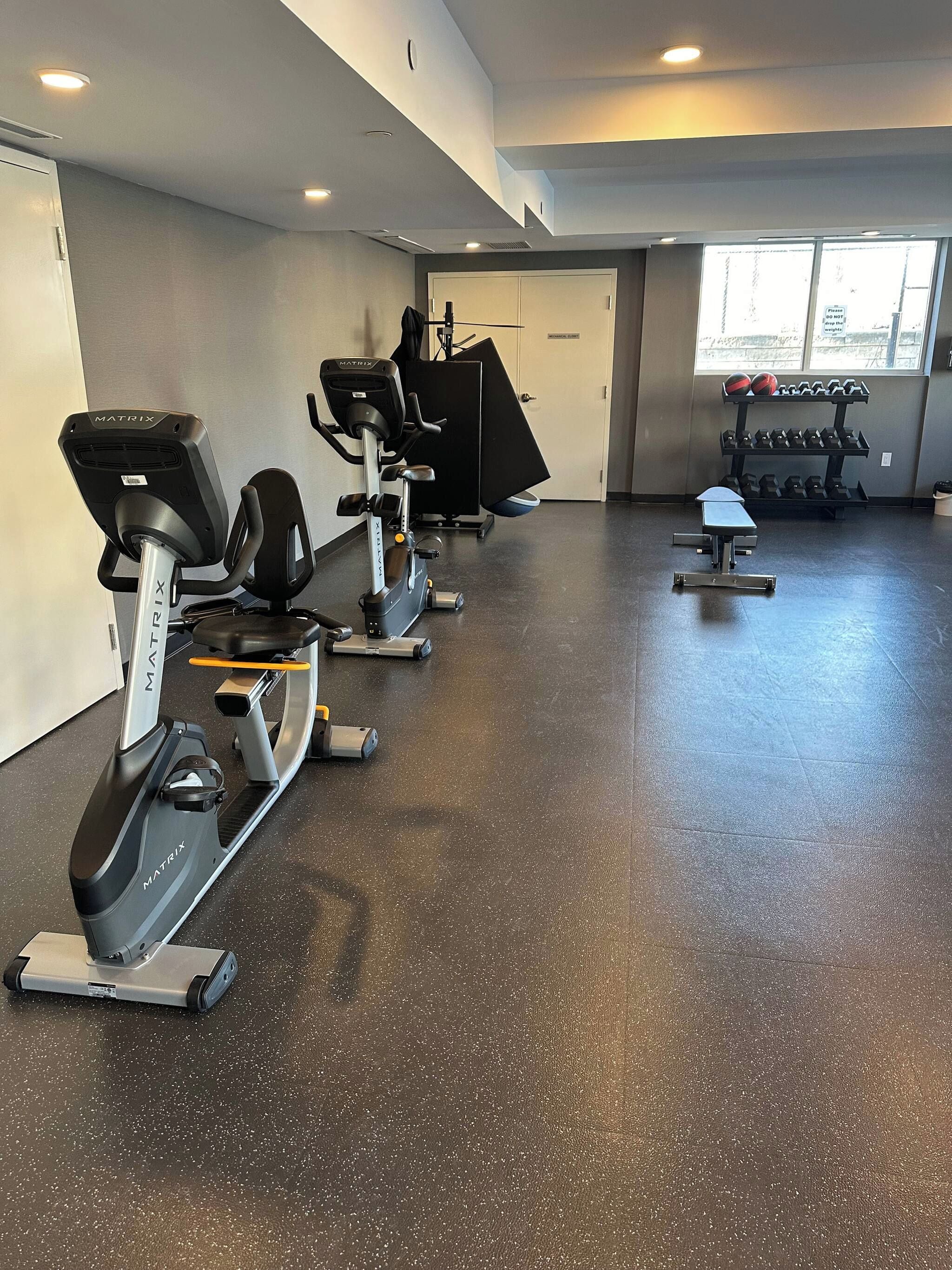 Een fitnessruimte met hometrainers, een loopband en gewichten.