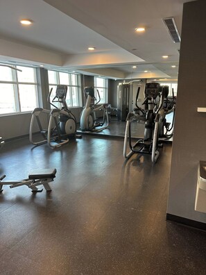 A gym with various exercise equipment, large windows, and a speckled floor. - Cozy one bed town house to explore city (Toronto)