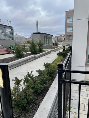 A rooftop garden with a pathway, greenery, and a building in the background. - Cozy one bed town house to explore city (Toronto)