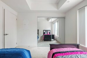 A bedroom with a large mirror, two beds, a wardrobe, and a window. - Cozy one bed town house to explore city (Toronto)