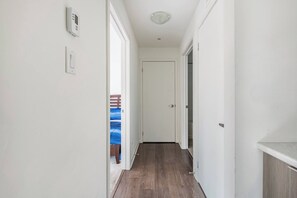 A hallway with a wooden floor, white walls, and a door at the end. - Cozy one bed town house to explore city (Toronto)