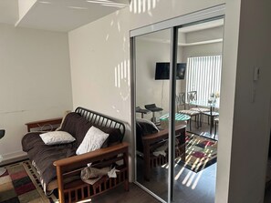 Ein Schlafzimmer mit einem Bett, einer Glastür, die in einen Essbereich führt, und einem an der Wand montierten Fernseher.