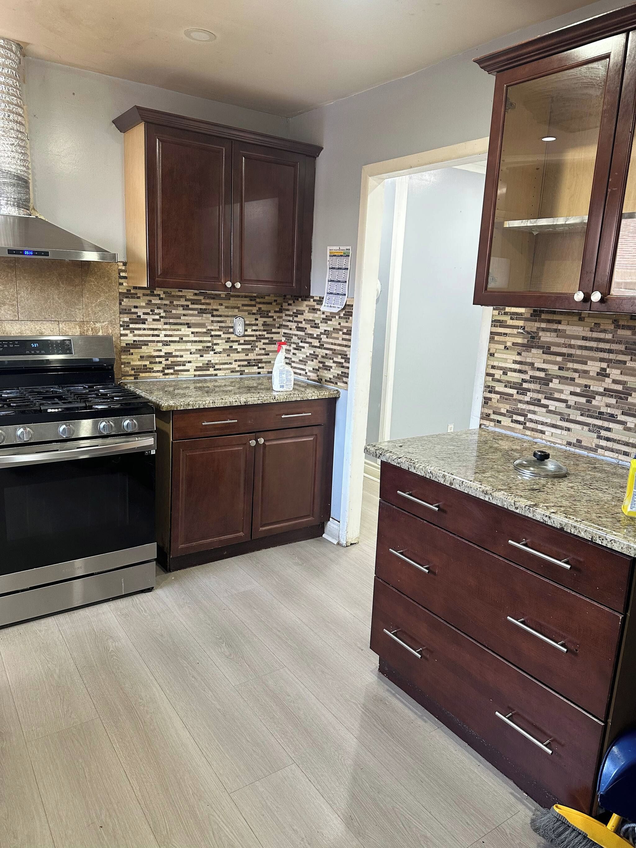 A kitchen with a stove, cabinets, and a tiled backsplash.