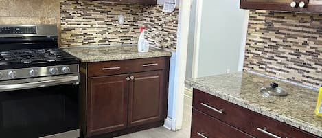 A kitchen with a stove, cabinets, and a tiled backsplash.