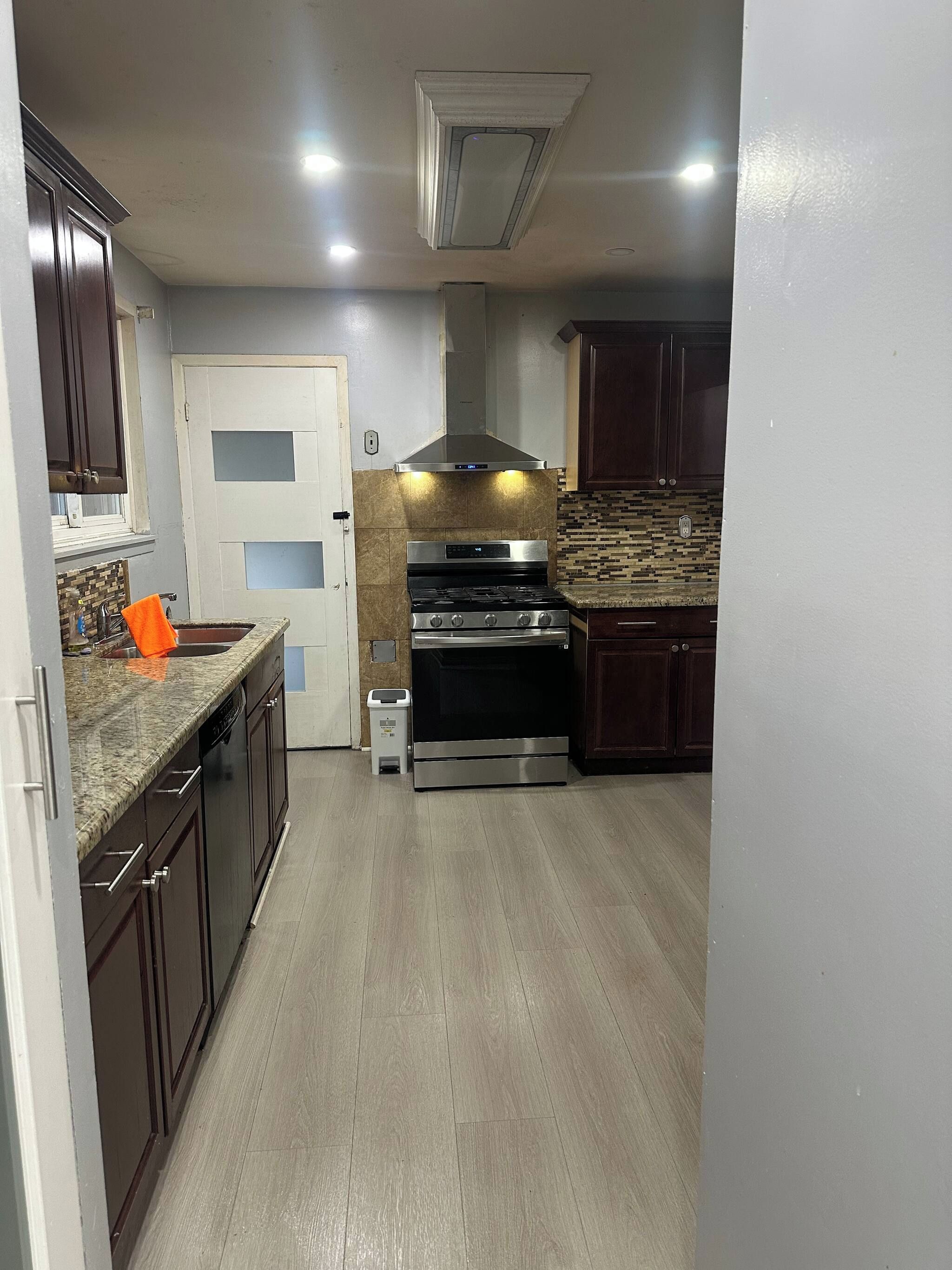 Una cocina con armarios de madera oscura, una campana extractora de acero inoxidable y un backsplash de azulejos.