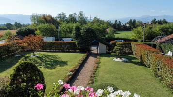 A well-maintained garden with a central pathway, surrounded by neatly trimmed hedges and flowering plants.