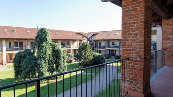 A courtyard with a brick building, a paved walkway, and a metal railing.