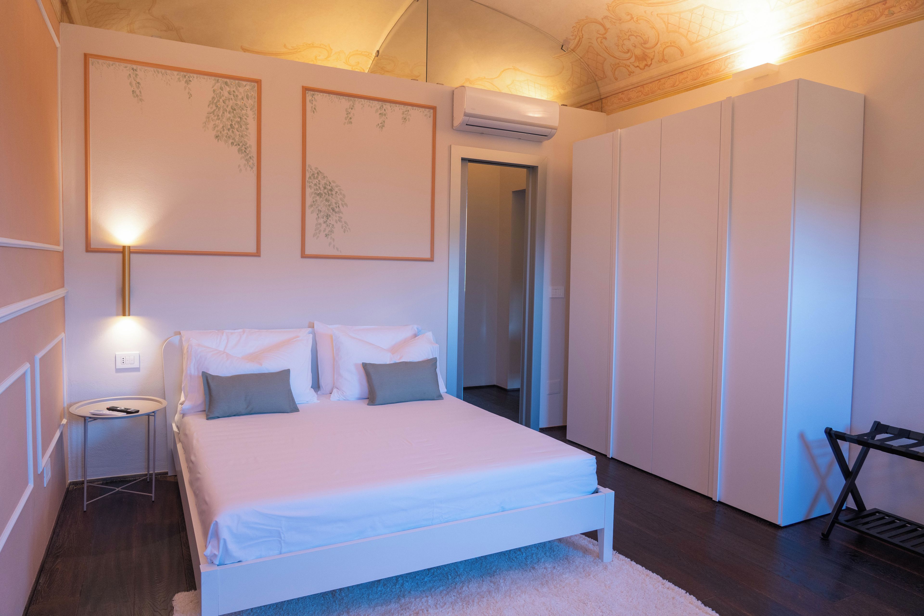 A bedroom with a bed, bedside tables, a wardrobe, and an air conditioning unit.