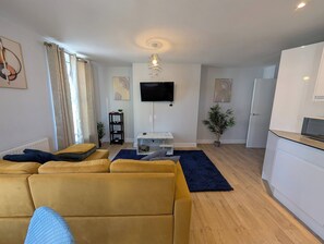 A living room with a sofa, a TV, a small table, and a plant. - Harbour Haven Dover Road Folkestone (Kent)