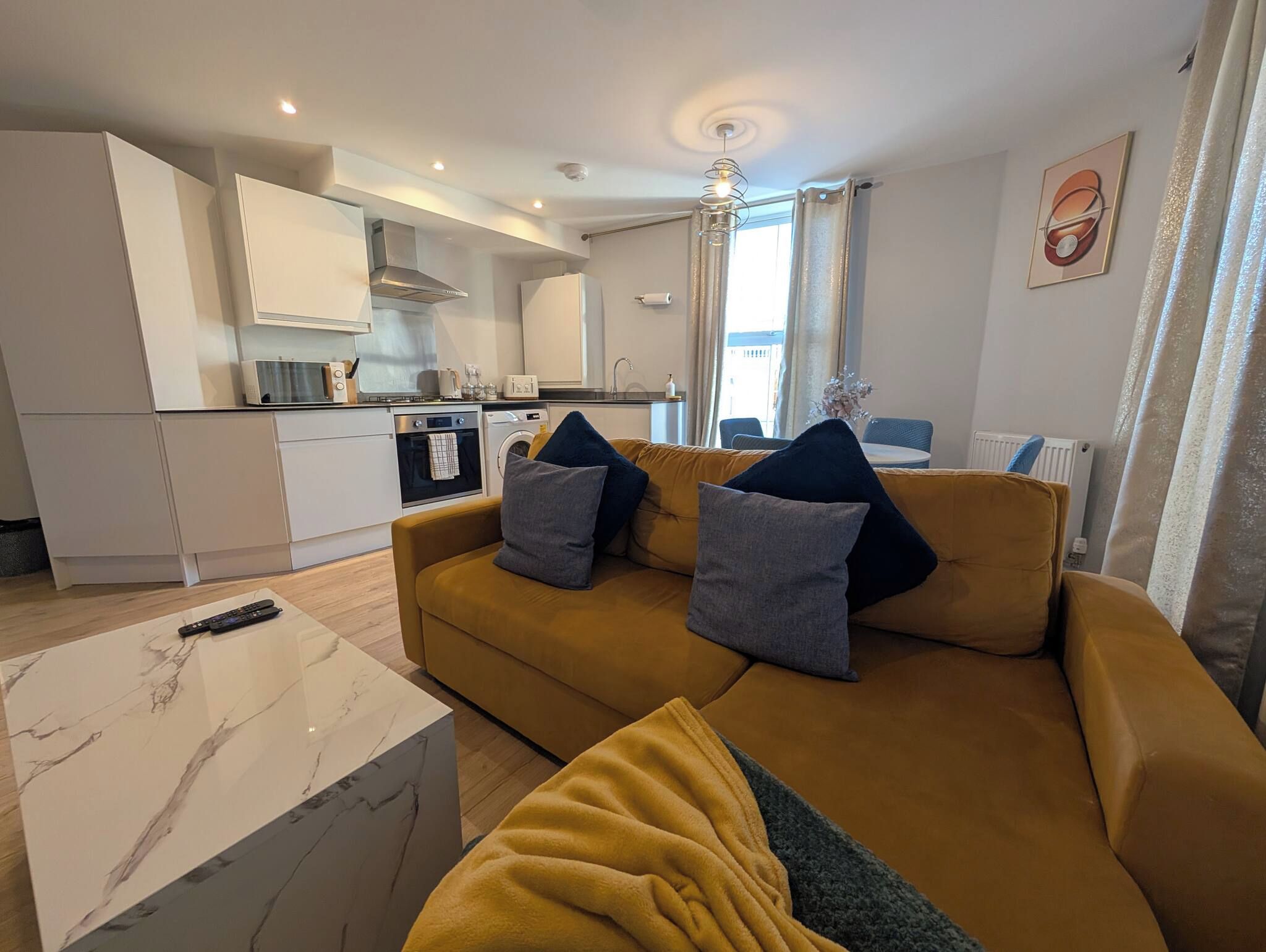 A modern living room with a sofa, a coffee table, and a kitchen in the background.