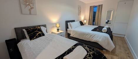 Ein Hotelzimmer mit zwei Betten, einem Nachttisch, einer Lampe, einem Spiegel und einer Deckenleuchte.