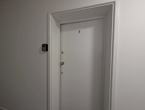 En vit dörr med siffran 5 på, en dörrklocka och ett nyckelhål.