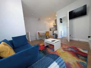 A modern living room with a blue sofa, a white coffee table, and a colorful rug. - Harbour Nest by Folkestone Harbour Arm (Folkestone)