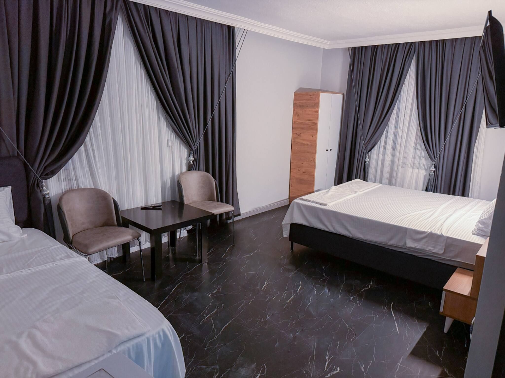 A hotel room with a bed, a desk, two chairs, and a wardrobe.