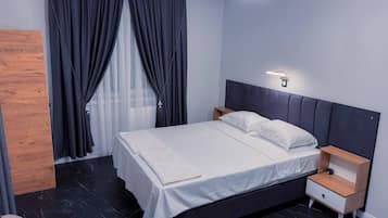 Een moderne slaapkamer met een bed, nachtkastjes, een houten paneel en een raam met gordijnen.